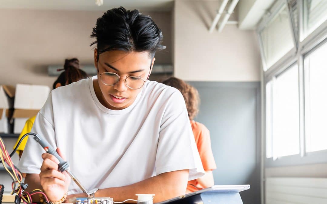 student wearing glasses working on hardware