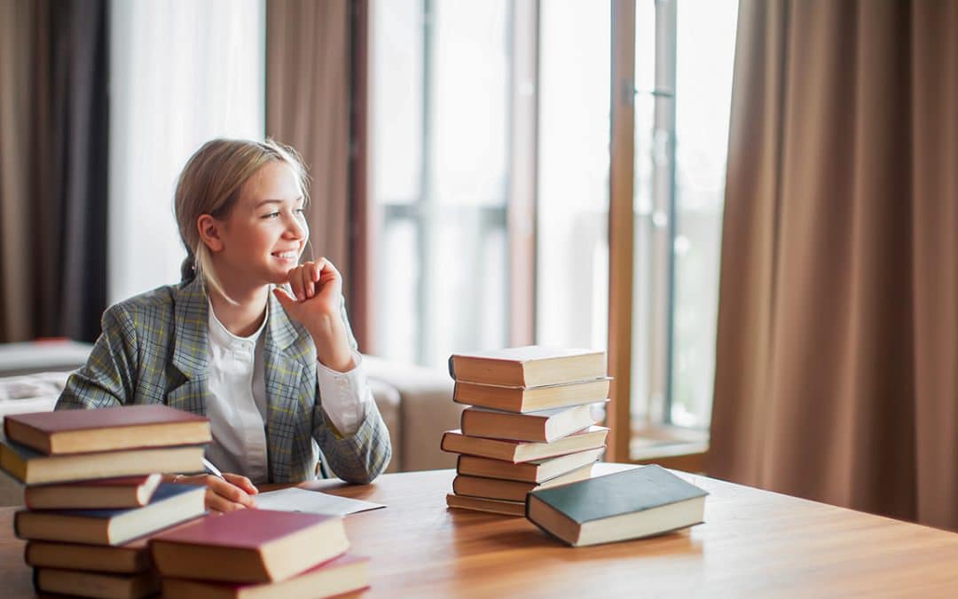 student smiling while writing in library