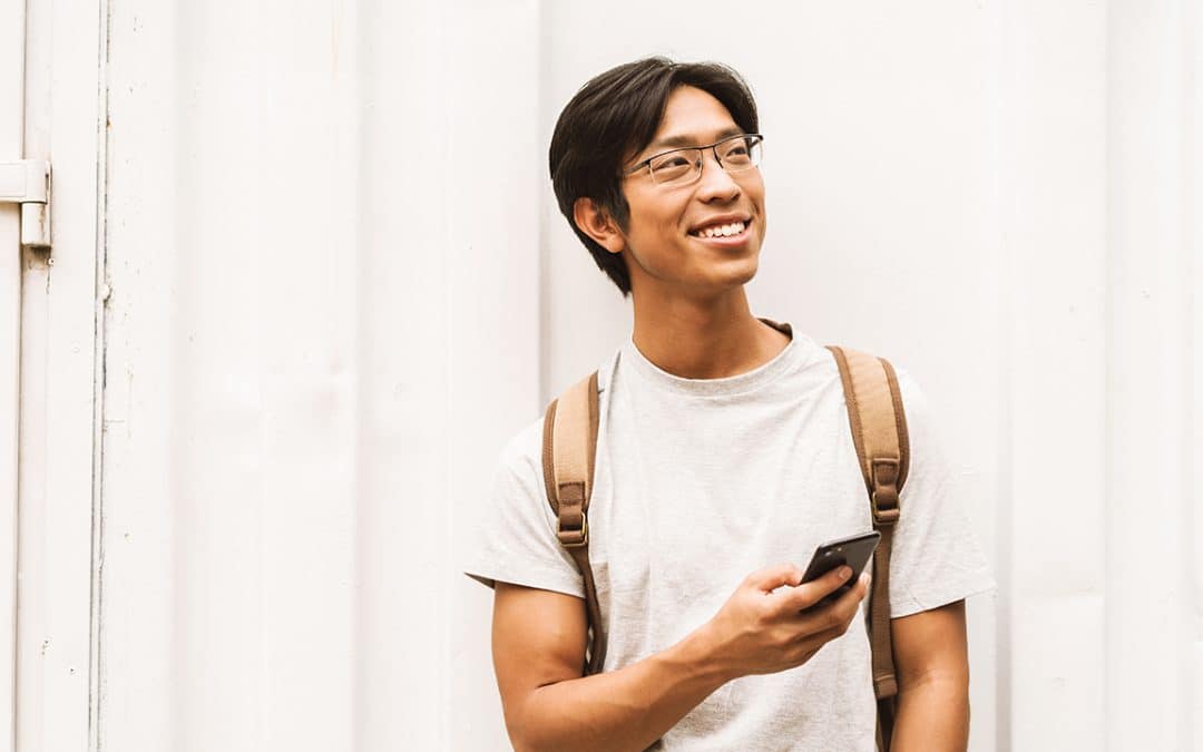 student wearing backpack holding phone