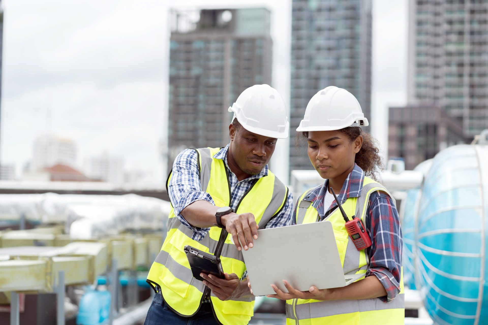Group of African American engineer worker working in sewer pipes area at construction site. Male engineer and woman engineer work with laptop computer for maintenance sewer pipes, water tank