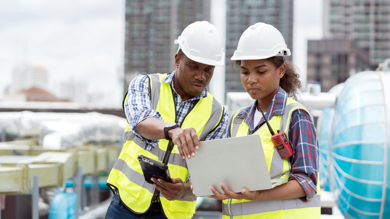 2 construction workers looking at laptop