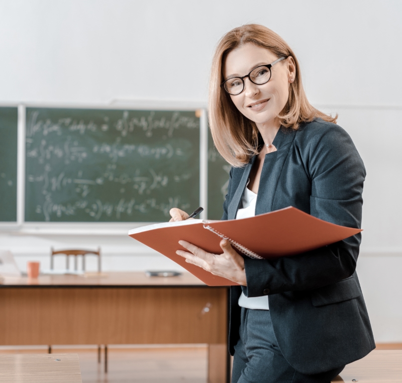 Teacher in classroom holding notebook
